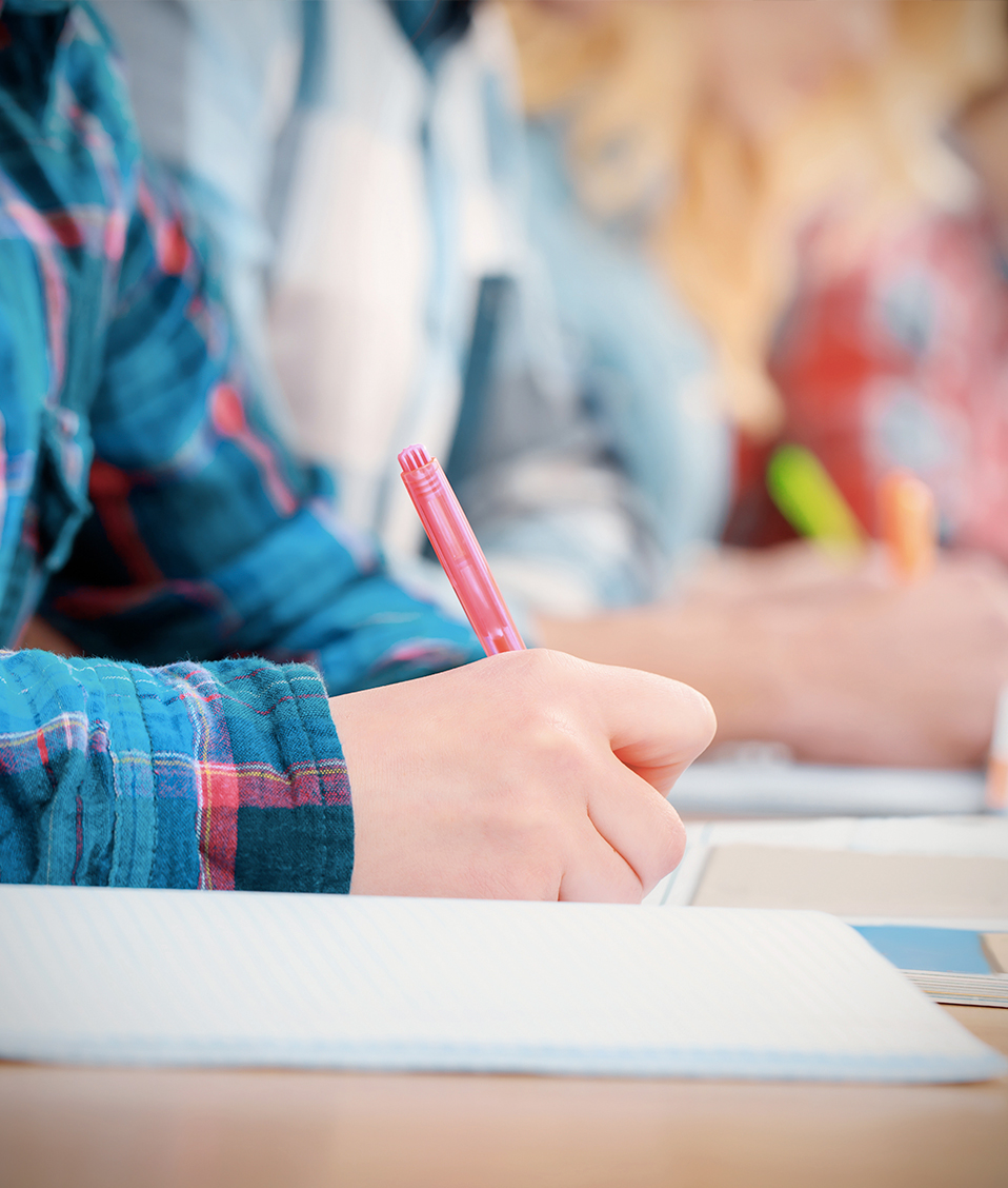 Estudiantes escribiendo apuntes mientras leen un libro