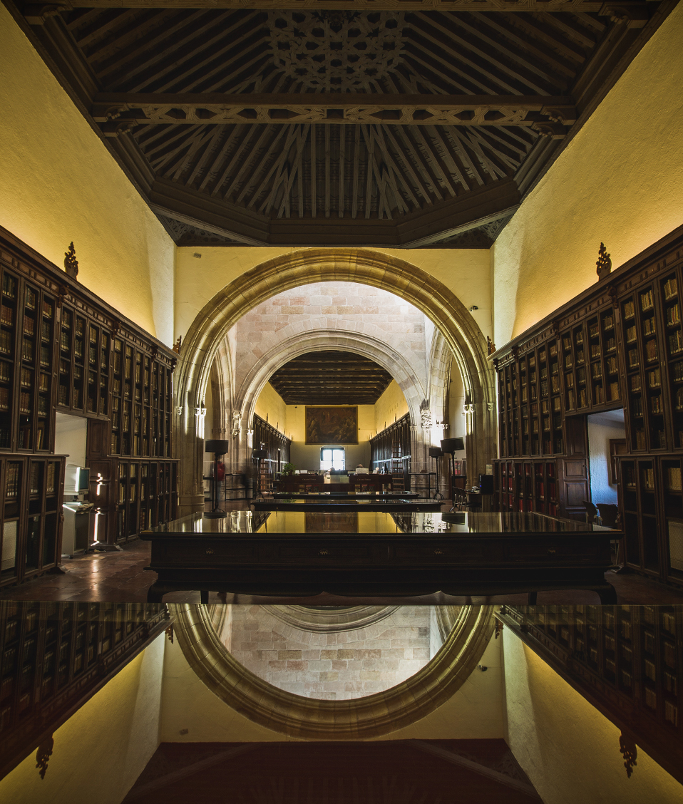 Pasillo biblioteca Hospital Real con mesas en el centro y estanterías con libros a ambos lados