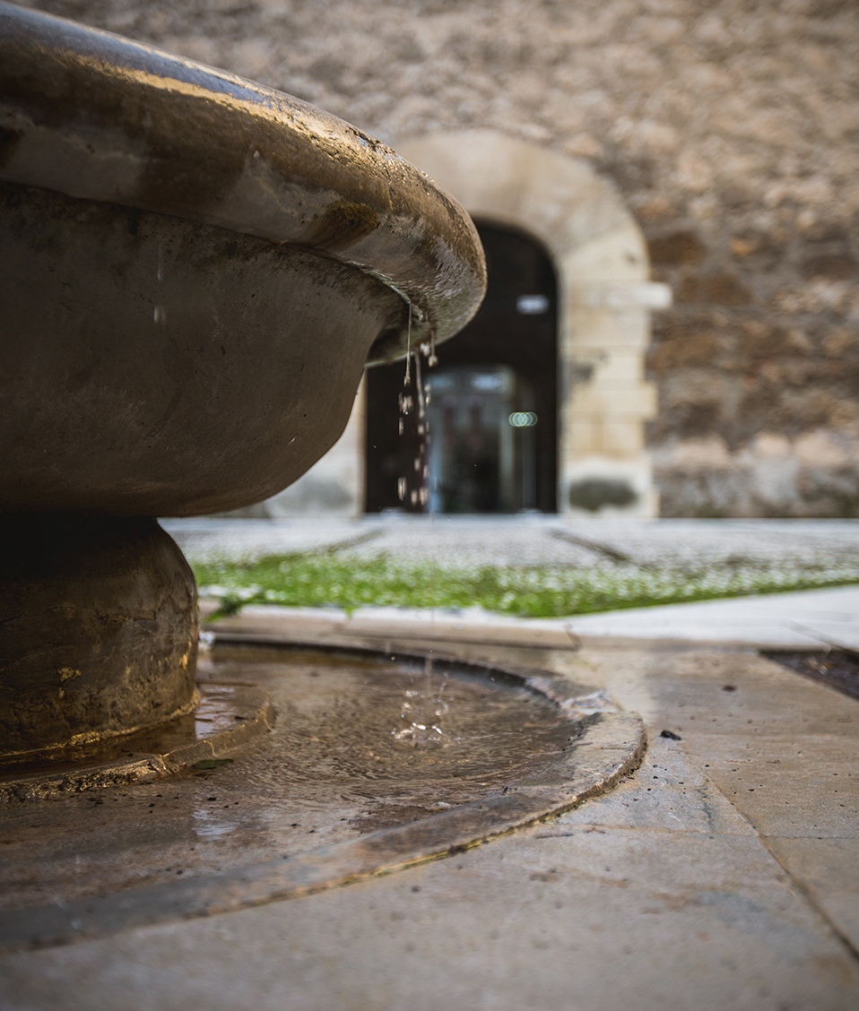 Fuente en patio del Hospital Real con puerta al fondo