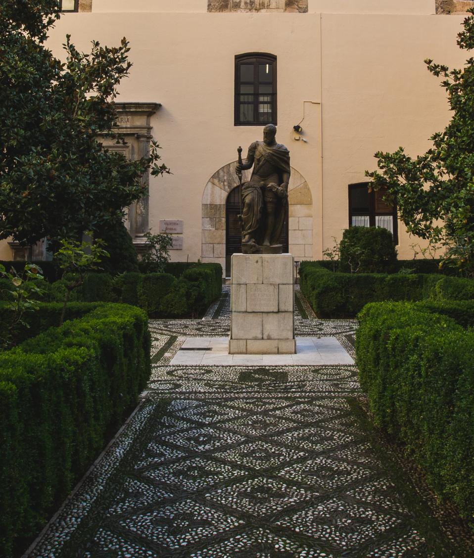 Patio con estatua en el centro y seto y árboles del Hospital Real